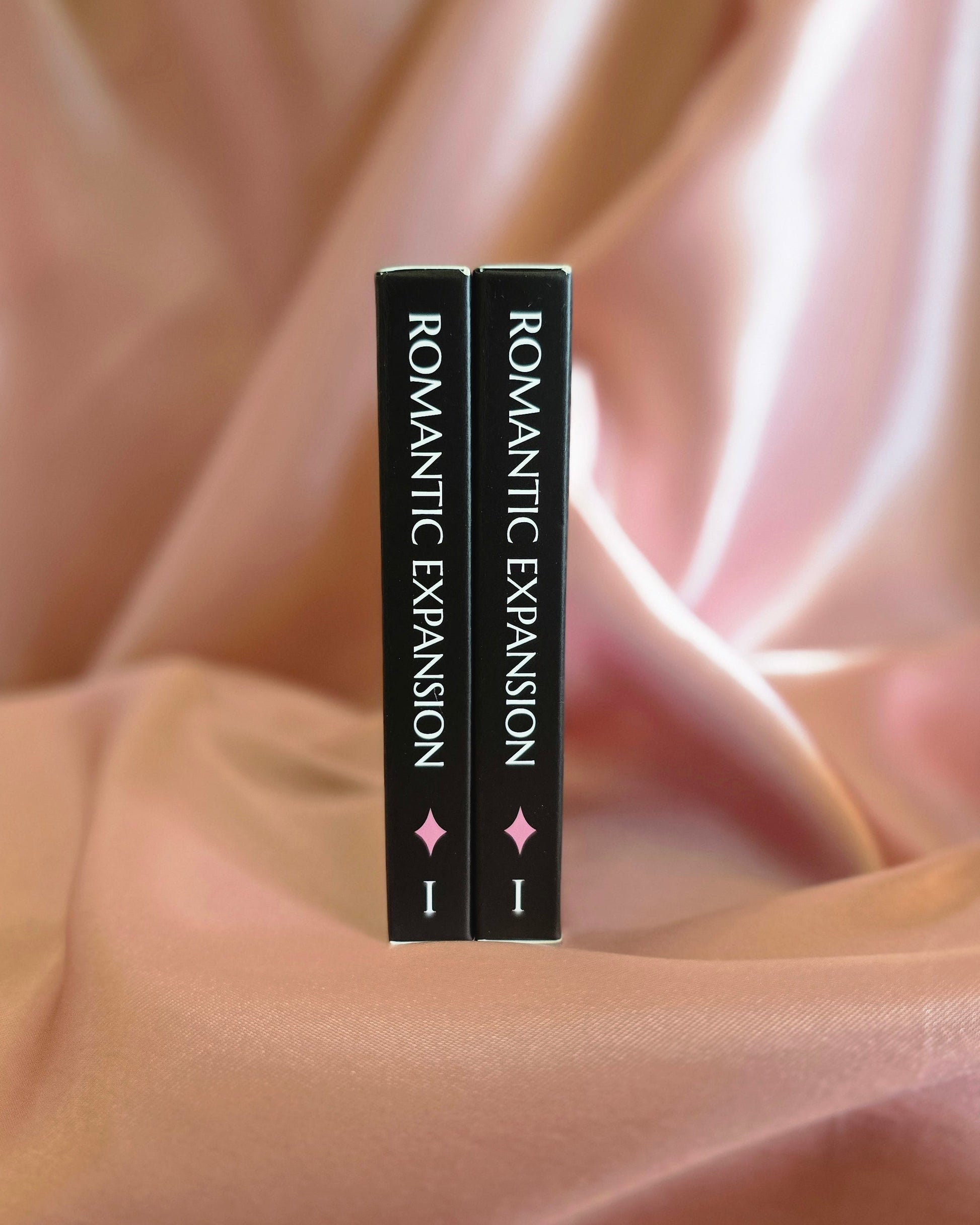 Two card packs titled 'Romantic Expansion' on a soft pink fabric background